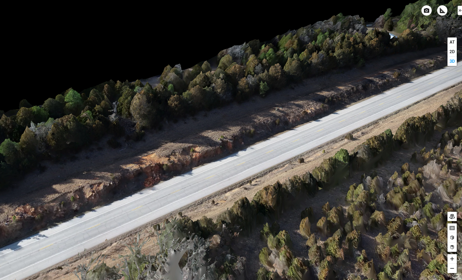 Aerial view of a quiet paved road winding through rugged terrain, bordered by dense autumn-colored forest and sparse vegetation